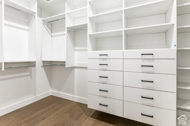 Built-in white custom closet system featuring multiple shelves, drawers with matte black hardware, and chrome hanging rods