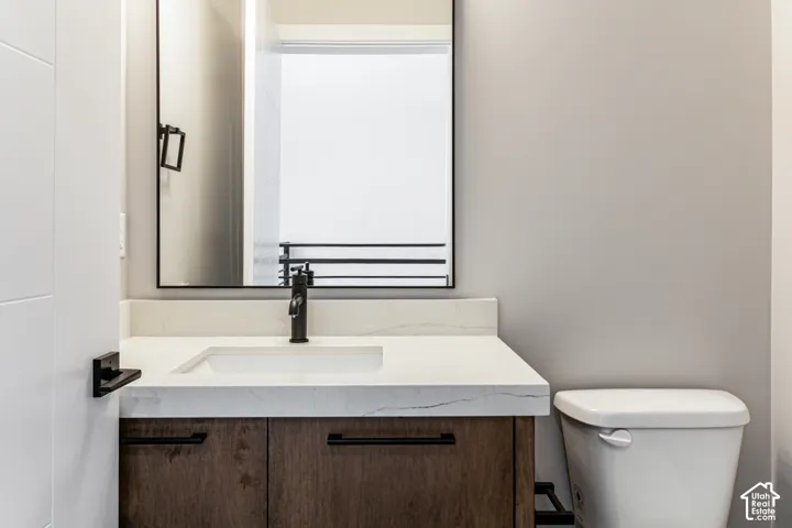 Wood-finish vanity with black hardware, white rectangular basin, and light-toned countertop