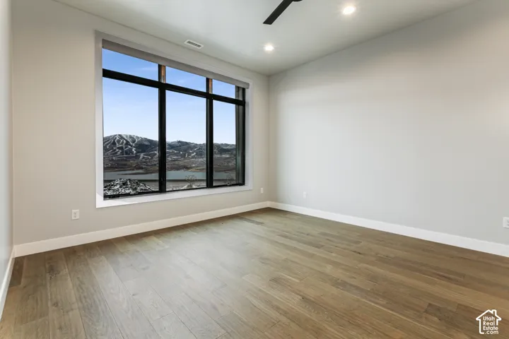 Expansive picture window, light wood-finish flooring, recessed lighting, ceiling fan, and neutral wall tones