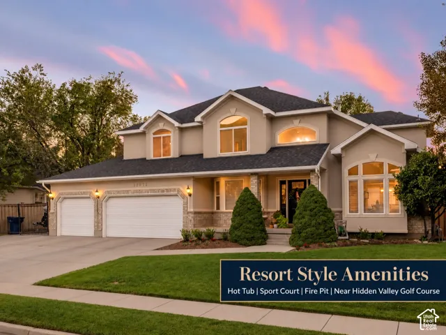 Multi-gabled exterior featuring light-toned siding, stone veneer accents, arched windows, and a three-car garage