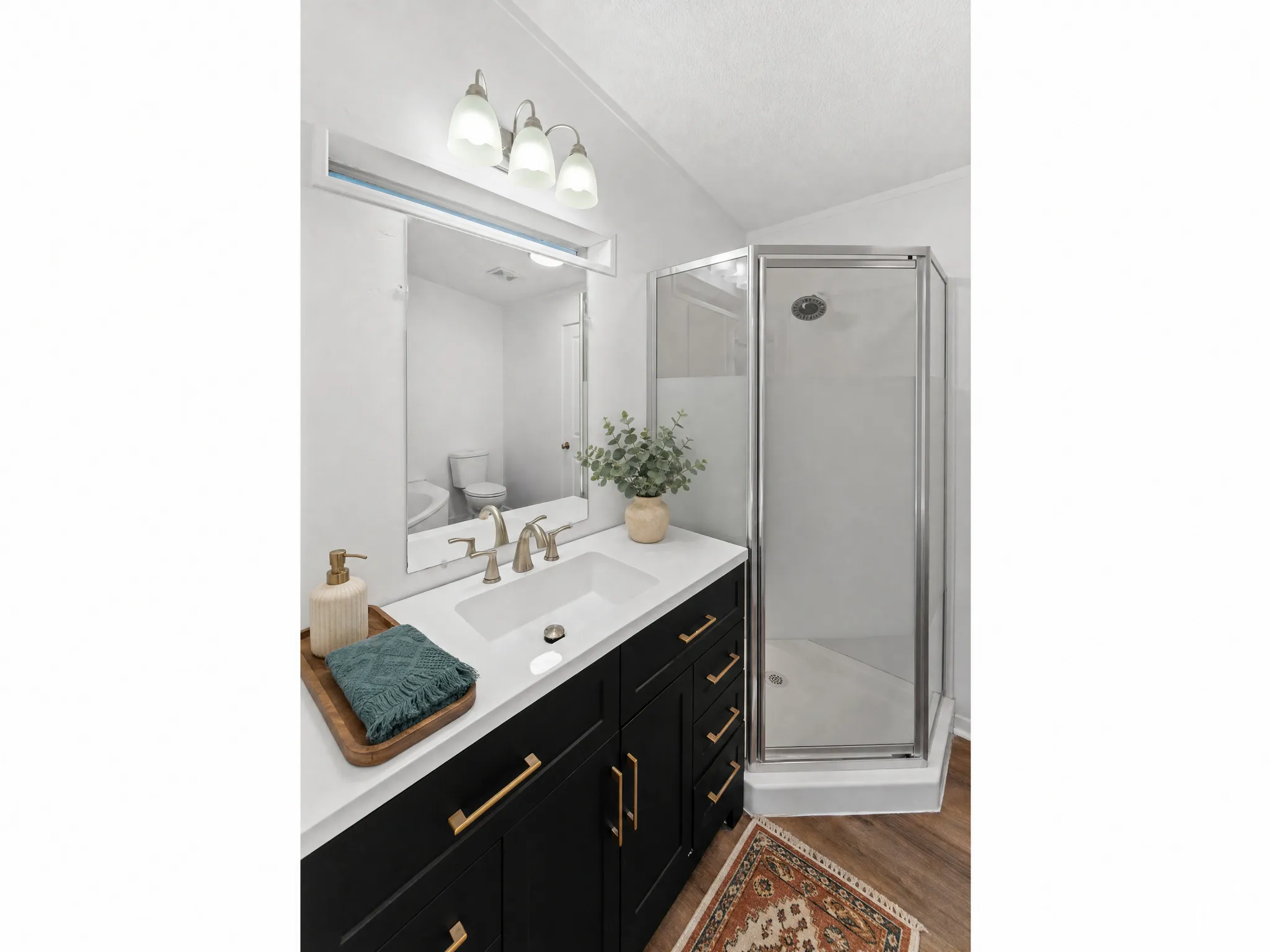 Contemporary bathroom featuring a dark wood-finish vanity with gold-tone hardware, a white undermount sink, and a white countertop