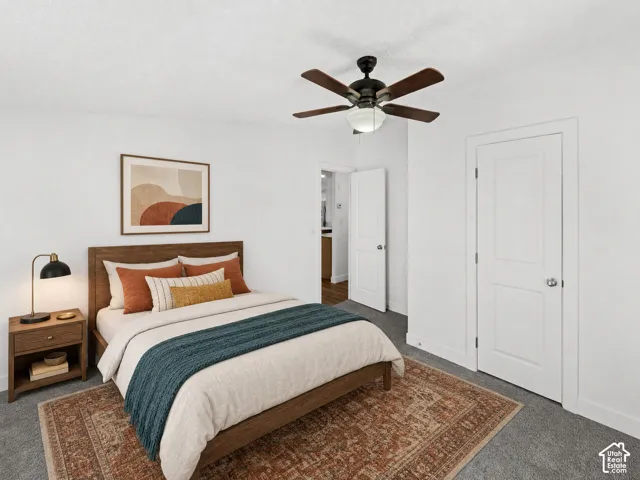 Textured carpeting, wood-finish bed frame, white interior doors, and a ceiling fan with integrated lighting