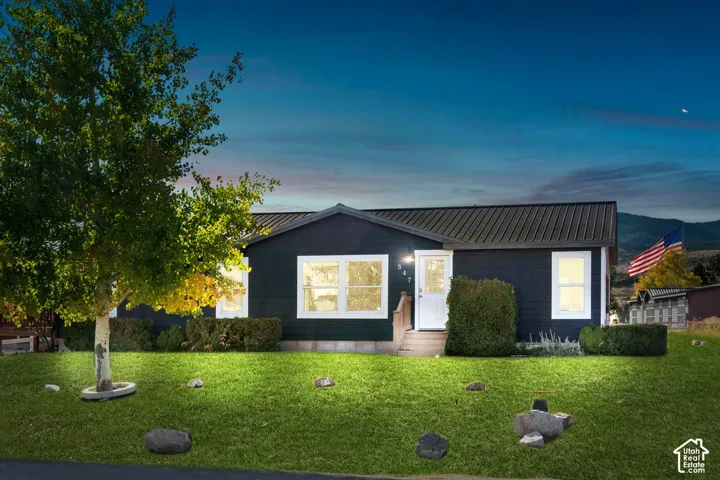 Dark-toned exterior siding with white trim windows and a white entry door