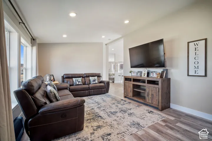 Spacious living area featuring wood-finish flooring, recessed lighting, and large windows with white trim