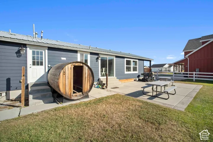 Exterior featuring blue siding, white trim, sliding glass door, white paneled door, and a metal roof