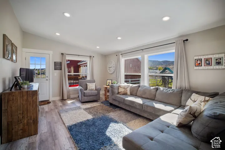 Recessed lighting, wood-finish flooring, vaulted ceiling, white trim, and a white paneled door with glass inserts