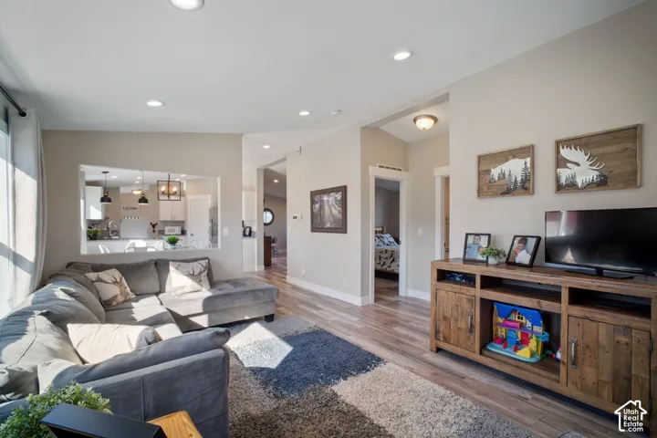 Recessed ceiling lighting, wood-finish flooring, and a pass-through window to the kitchen
