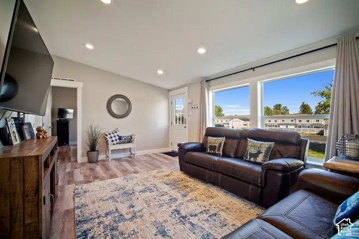 Vaulted ceiling with recessed lighting, wood-finish flooring, white trim details, and large picture windows