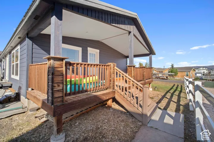 Covered front porch with wood railings and stairs, featuring dark horizontal siding and a visible white window frame