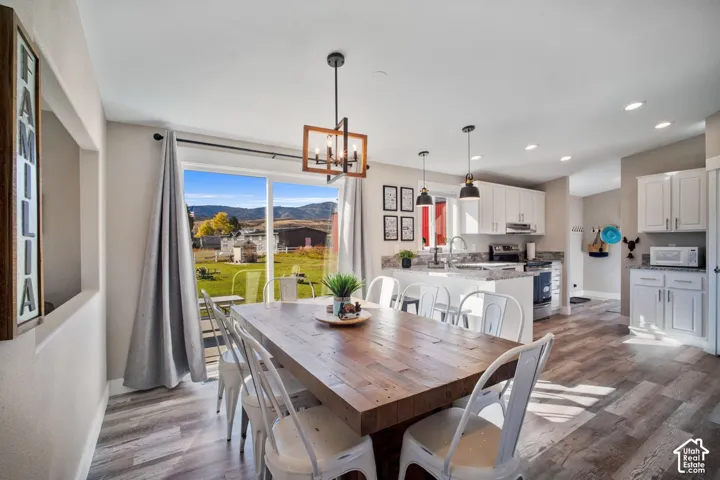 Open concept living space featuring wood-finish flooring, white cabinetry, and recessed lighting