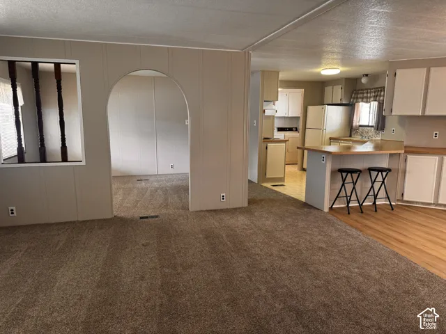 Kitchen with wood-finish flooring, white cabinetry, and a peninsula breakfast bar