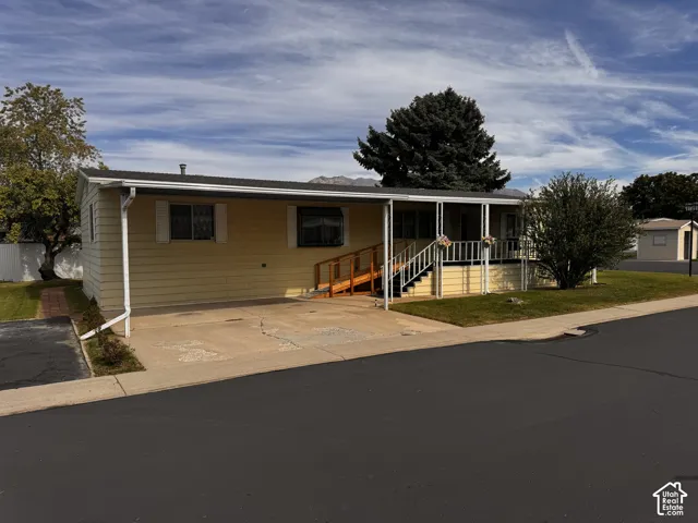 Single-story residence featuring light yellow siding, a covered porch, and a wooden ramp