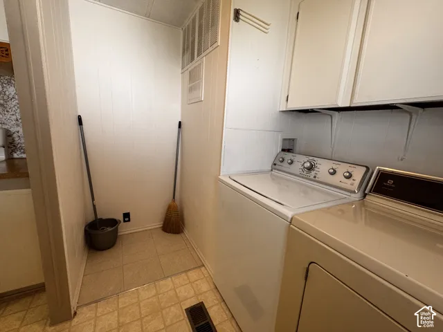 Utility area featuring white paneled walls, a built-in shelf, and overhead cabinetry