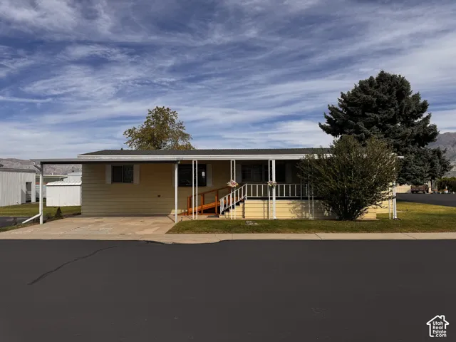 Single-story residence featuring a covered carport, front porch with white railing, and a wooden ramp entry