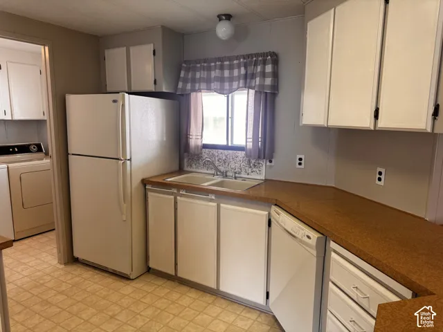Kitchen featuring white cabinetry, laminate countertops, dual basin sink, and tile-finish flooring