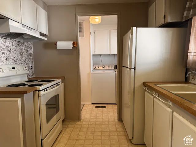 Kitchen featuring white appliances, upper and lower cabinetry, a double basin sink, and wood-finish countertops