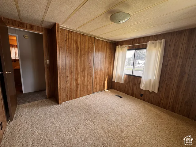Wall-to-wall carpeting with wood-finish wall paneling, dual windows, and built-in closet storage
