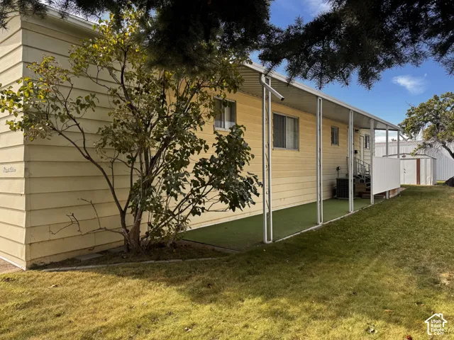 Outdoor patio with a metal awning, artificial turf, and a storage shed