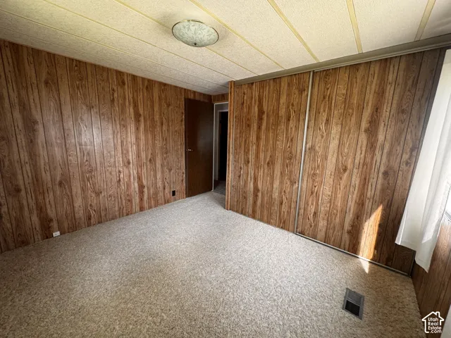 Wood-finish wall paneling, light-toned carpet, and a flush-mount ceiling fixture