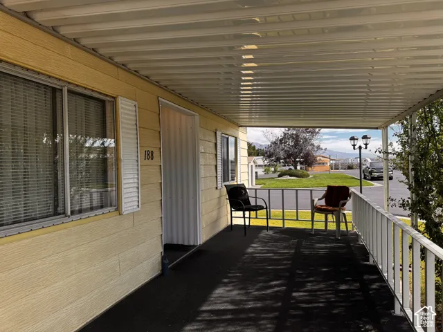 Covered porch with an aluminum railing, textured yellow siding, and an opaque exterior door