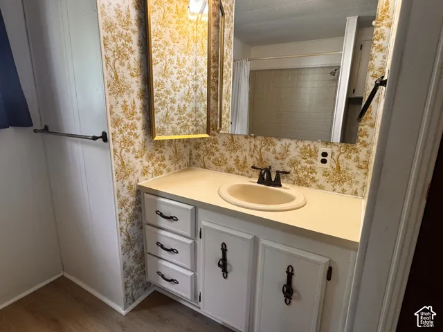 Vanity with integrated sink, gold-framed medicine cabinet, and decorative wallpaper accent