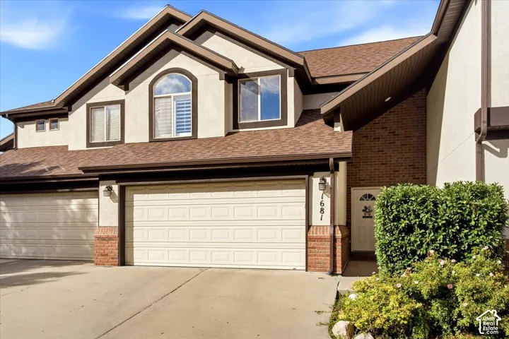 Stucco exterior with brick accents, arched window, and two-car garage