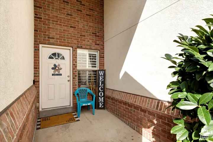 Brick exterior with stucco accents, white entry door with an arched transom, and a window with plantation shutters