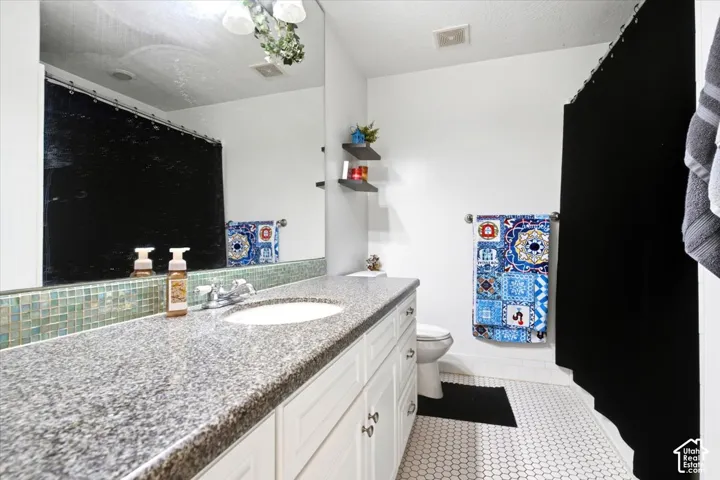 Vanity with a granite-style countertop, integrated sink, and white cabinetry