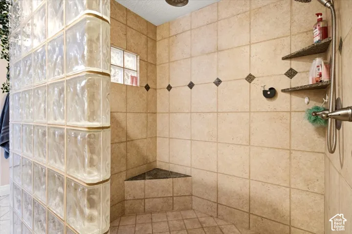 Tiled shower with glass block wall, integrated shower bench, and recessed wall shelving