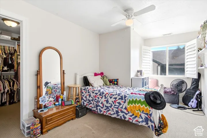 Recessed window with plantation shutters, ceiling fan, and walk-in closet with built-in organization system