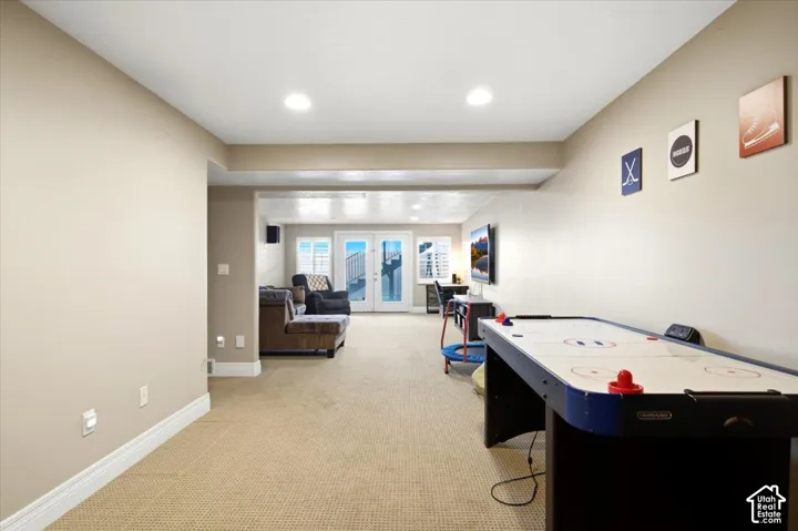 Recessed lighting, neutral wall paint, white trim, carpeted flooring, and a broad cased opening