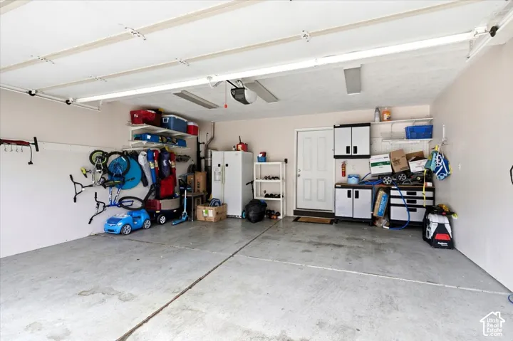 Garage featuring a concrete floor, built-in shelving, and a pedestrian door