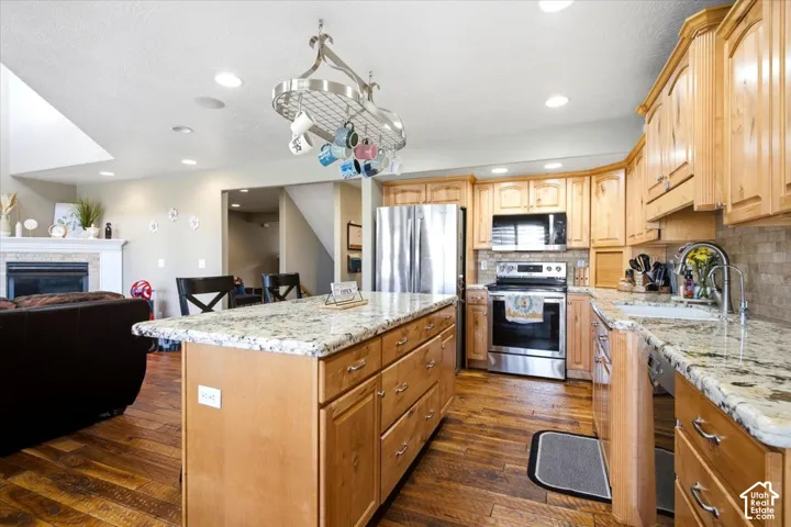 Spacious kitchen with a center island, light wood cabinetry, stone countertops, and stainless steel appliances