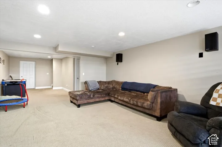 Recessed ceiling lighting, wall-mounted speakers, and light-colored carpet flooring
