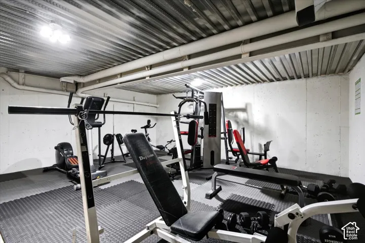 Dedicated fitness area featuring a corrugated metal ceiling and exposed utility piping