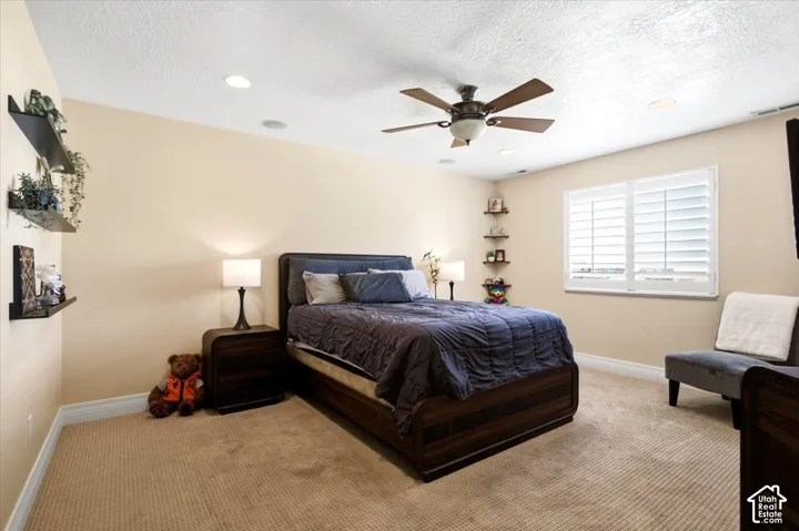 Recessed lighting, ceiling fan, window with plantation shutters, wall-mounted shelving, and carpeted flooring