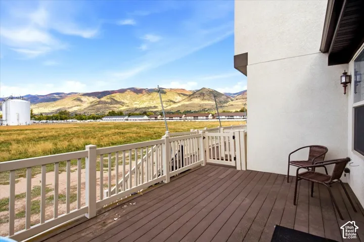 Spacious outdoor deck with wood-finish flooring, white railing, and an exterior wall light fixture