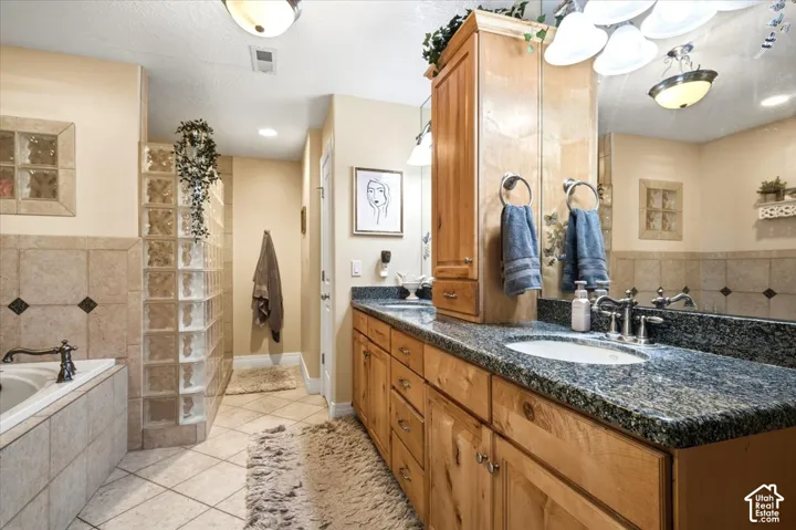 Double vanity with dark granite countertop and light wood cabinetry
