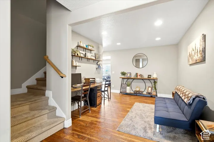 Recessed lighting, wood-finish flooring, staircase with carpeted treads, wood handrail, and built-in shelving