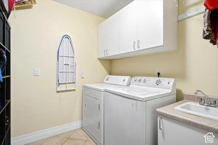 Laundry area featuring wall-mounted cabinetry, a built-in sink with countertop, and tile flooring