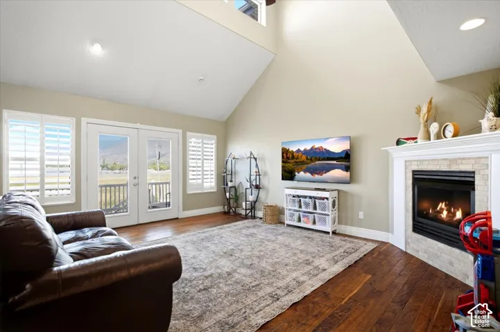 Vaulted ceiling with recessed lighting, wood-finish flooring, and a fireplace with a tiled surround and mantel