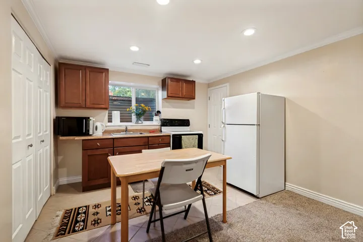 Compact kitchen featuring wood-finish cabinetry, tile flooring, and recessed lighting