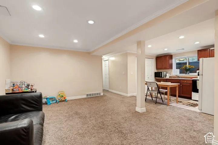 Recessed ceiling lighting, crown molding, and wood-finish cabinetry