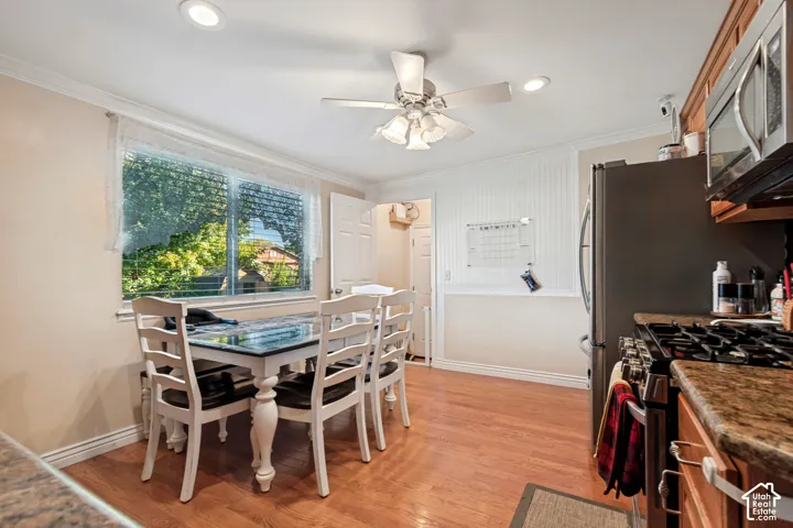 Wood-finish flooring, recessed lighting, crown molding, beadboard wainscoting, and a ceiling fan with light fixture