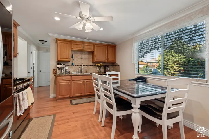 Wood-finish flooring, recessed lighting, ceiling fan, wood cabinetry, and a tile backsplash