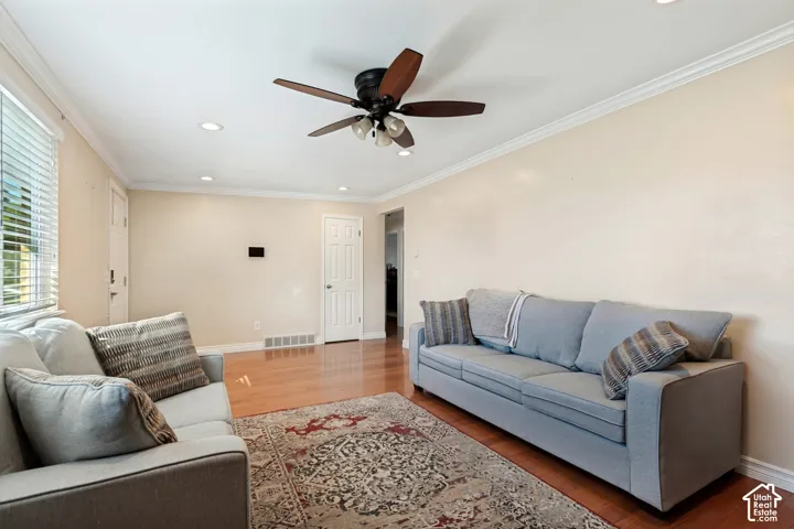 Hardwood flooring throughout, crown molding, recessed lighting, and a ceiling fan with integrated lighting