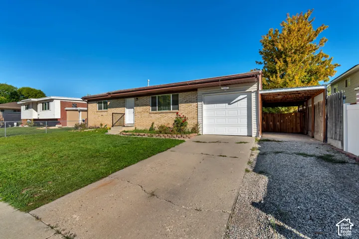 Brick exterior with a single-car garage, concrete driveway, and carport with a privacy fence