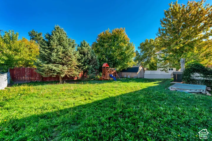 Expansive green lawn with mature trees and a privacy fence