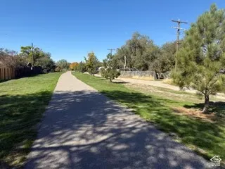 Paved pathway bordered by manicured green spaces and mature trees