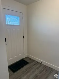 Welcoming entry featuring a solid wood panel door with transom window, wood-finish plank flooring, and clean white walls with crisp trim detailing
